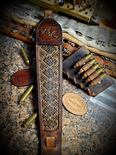 Buffalo leather rifle slings with tooled upper and rattlesnake inlay.